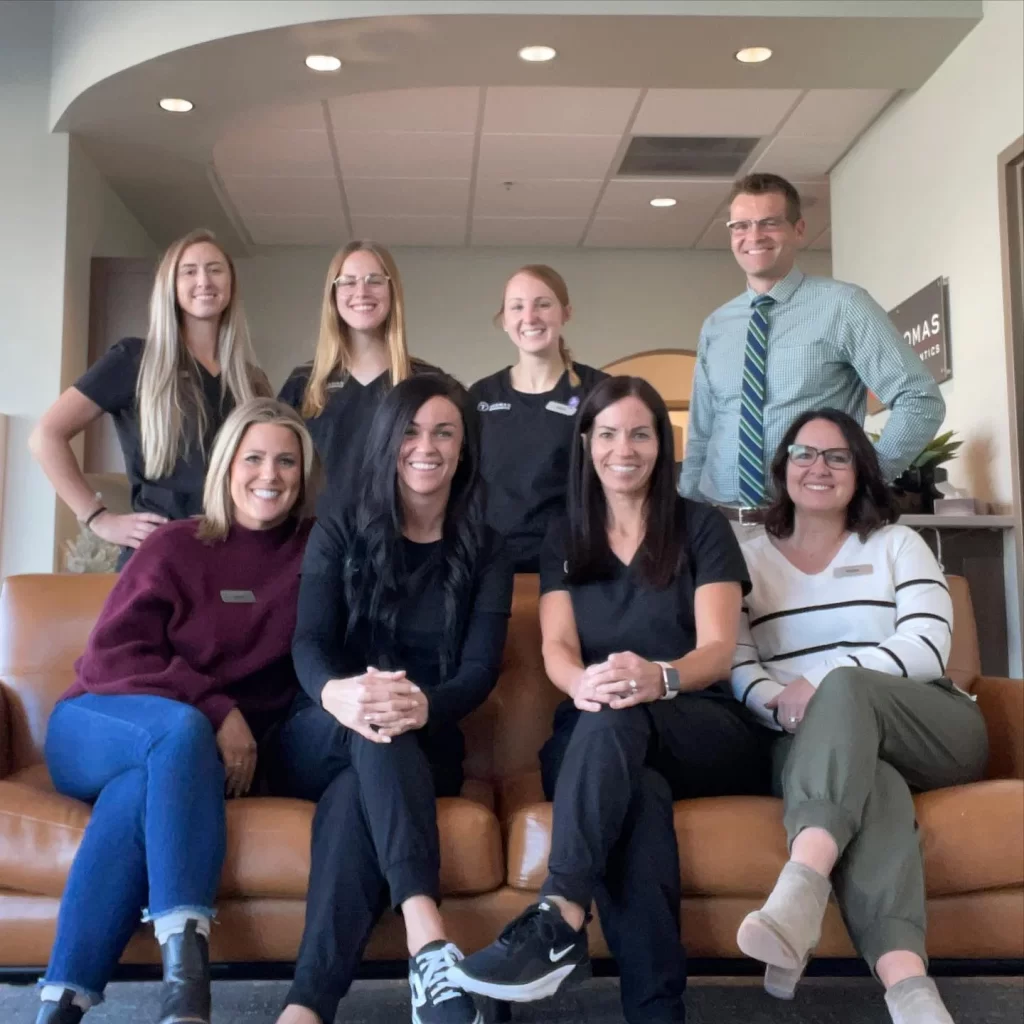 Dental office staff group photo, smiling in lobby.